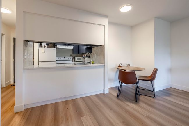 Kitchen featuring tasteful backsplash, white appliances, under cabinet range hood, and wood finished floors | Image 10