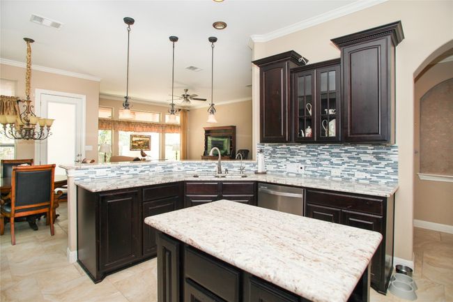 Kitchen with stainless steel dishwasher, a sink, ornamental molding, a peninsula, and decorative backsplash | Image 10