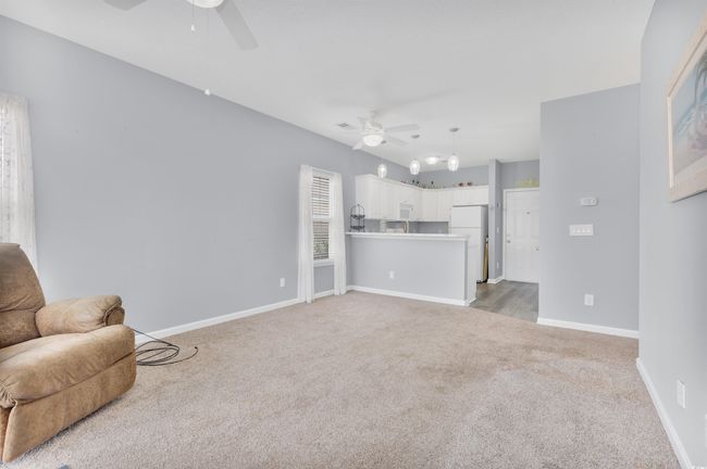 Carpeted living area with ceiling fan and baseboards | Image 11