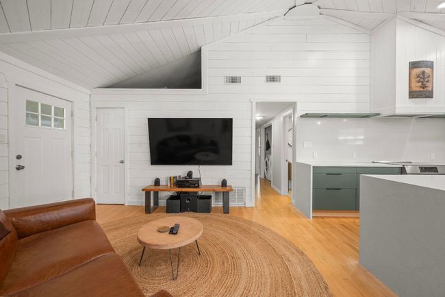 Living room with light wood-style flooring, vaulted ceiling with beams, and visible vents | Image 8