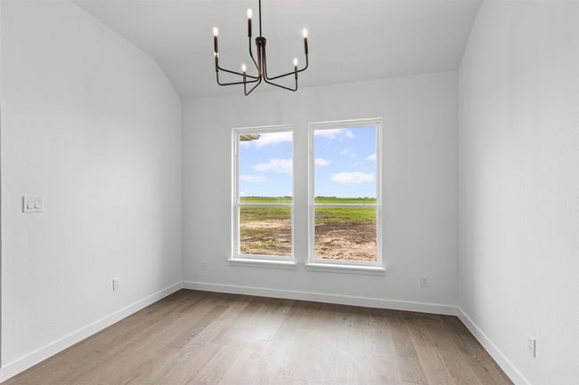 Unfurnished dining area with baseboards, a notable chandelier, wood finished floors, and vaulted ceiling | Image 19