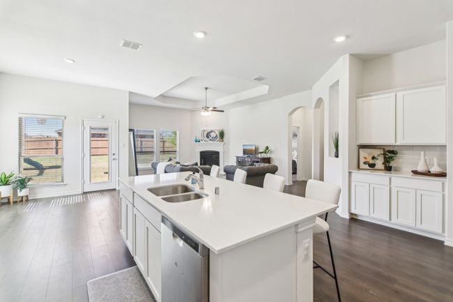Kitchen with a fireplace, ceiling fan, stainless steel dishwasher, arched walkways, and a sink | Image 12