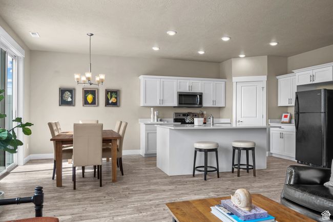 Kitchen featuring a kitchen breakfast bar, light countertops, white cabinets, a chandelier, and stainless steel appliances | Image 8