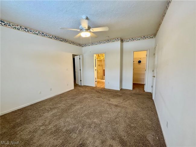 Unfurnished bedroom with a textured ceiling, carpet floors, ceiling fan, and ensuite bathroom | Image 15