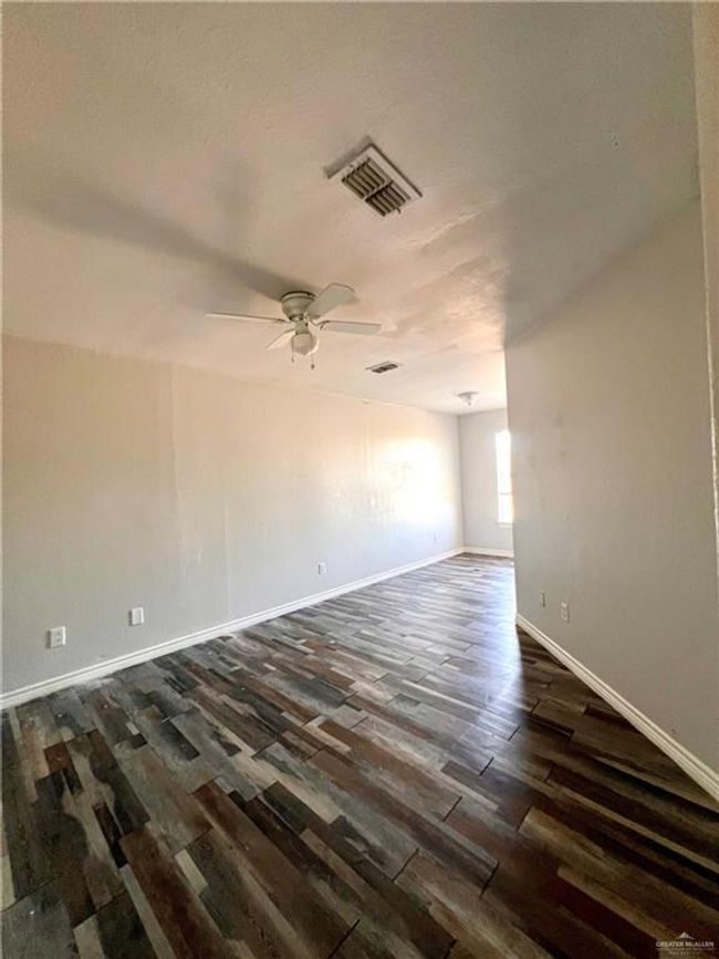 Unfurnished bedroom with baseboards, visible vents, dark wood-style flooring, and ceiling fan | Image 6