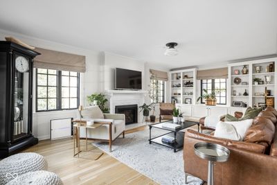 A large living room flooded with light centers around a beautiful fireplace with custom built-ins. | Image 2