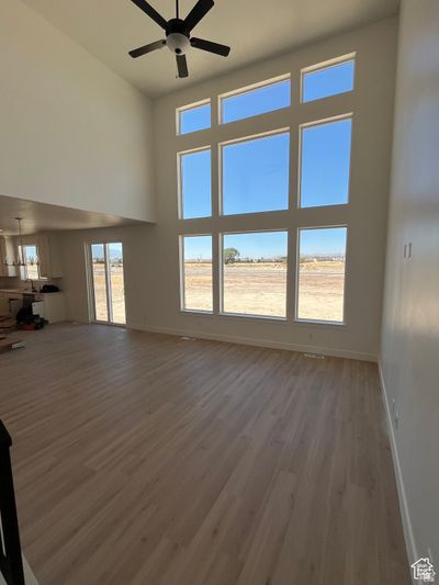 Unfurnished living room with a high ceiling, ceiling fan, and light hardwood / wood-style flooring | Image 2