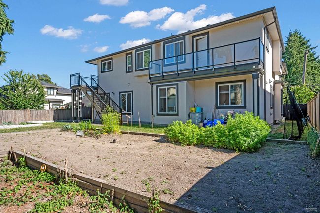 Back of house with a balcony, a fenced backyard, stucco siding, and stairs | Image 40