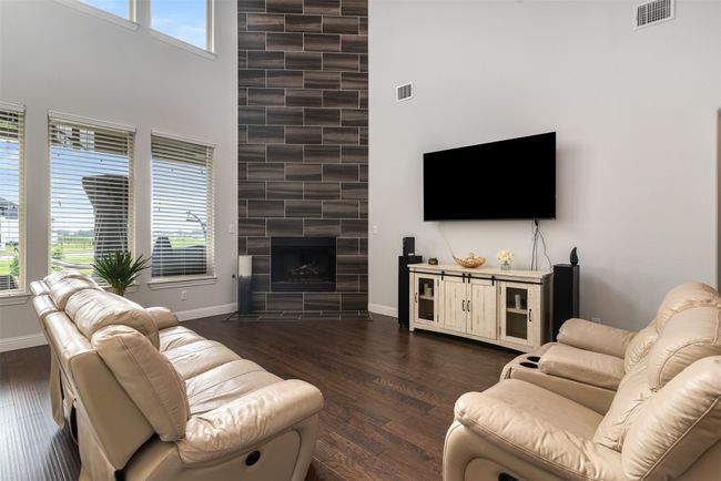 Living area with baseboards, visible vents, a large fireplace, and dark wood-style floors | Image 7