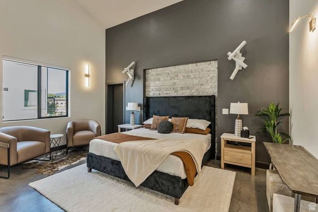Bedroom with concrete flooring, a fireplace, and a towering ceiling | Image 18