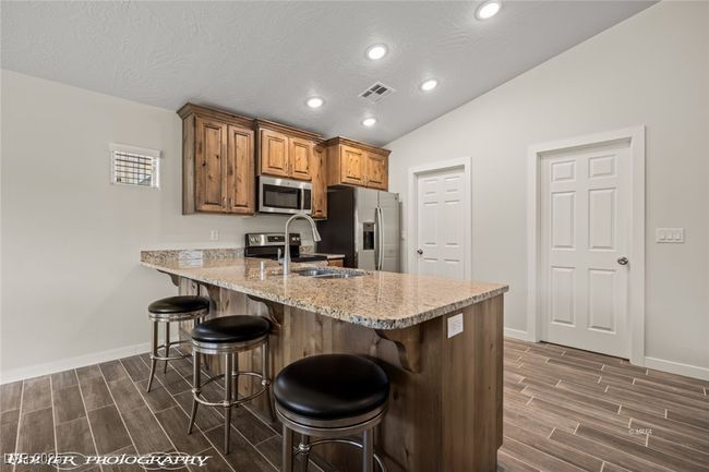 Kitchen featuring stainless steel appliances, wood finish floors, a breakfast bar area, a sink, and recessed lighting | Image 29