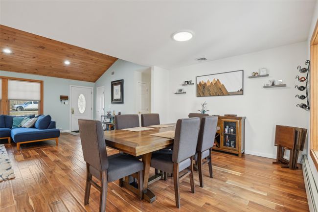 Dining room with visible vents, baseboards, light wood-style floors, lofted ceiling, and baseboard heating | Image 13