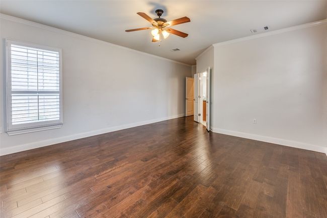 Spare room featuring visible vents, crown molding, baseboards, ceiling fan, and dark wood finished floors | Image 13