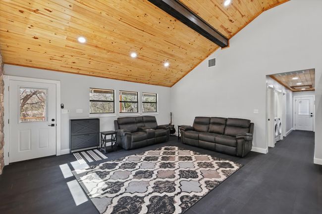 Living room with high vaulted ceiling, wood finished floors, wood ceiling, and baseboards | Image 16