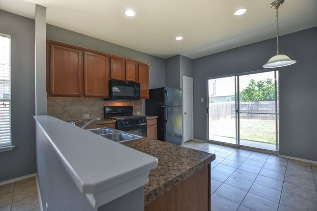 Kitchen with black appliances, a sink, baseboards, brown cabinetry, and recessed lighting | Image 20