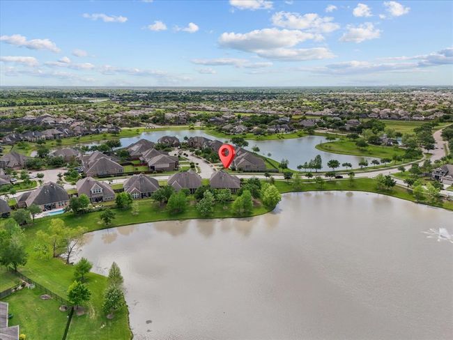 This aerial photo showcases a serene residential neighborhood with spacious homes surrounded by lush greenery and multiple lakes. The highlighted property is located on water front property offering picturesque views and a tranquil atmosphere. | Image 41