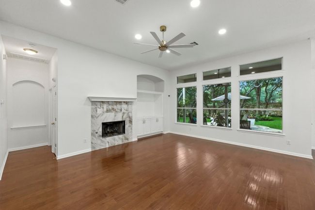 Family room with picture windows to a backyard haven, wood flooring, recessed lighting, gas fireplace, built-ins and new ceiling fan and fresh interior paint. | Image 6