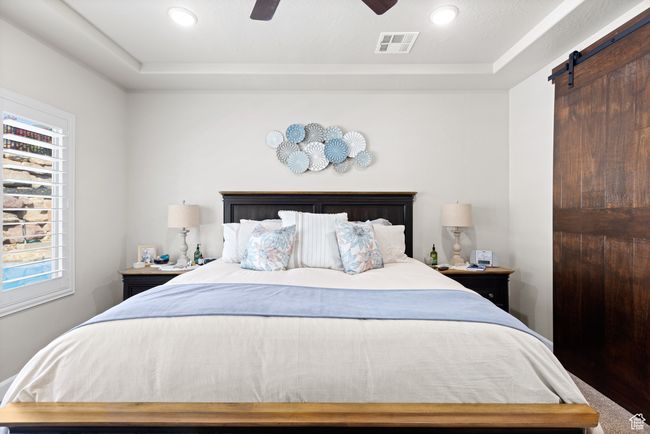 Bedroom featuring multiple windows, a barn door, recessed lighting, a raised ceiling, and a ceiling fan | Image 35