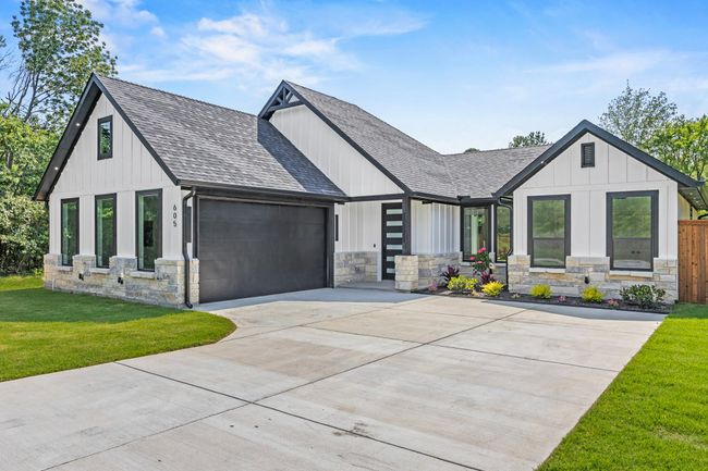 Modern inspired farmhouse featuring a shingled roof, stone siding, an attached garage, and driveway | Image 4
