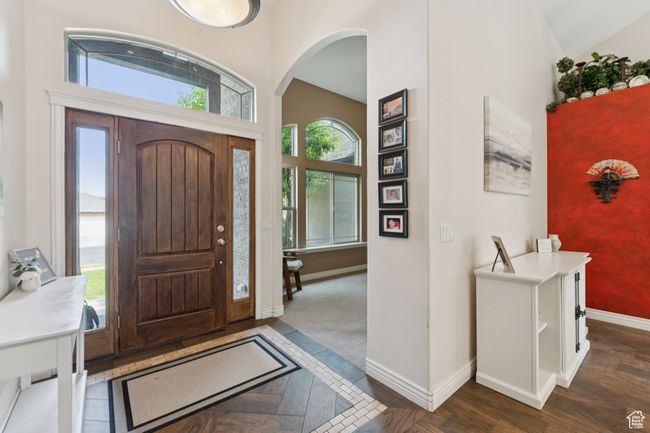 Foyer entrance featuring baseboards, arched walkways, dark wood-style flooring, and a high ceiling | Image 4