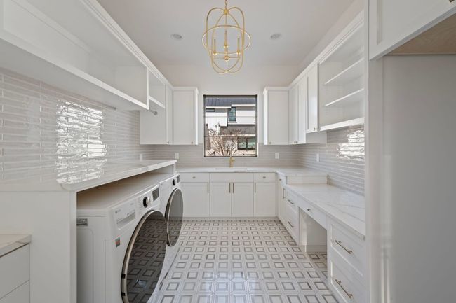 Laundry area featuring cabinet space, washer and clothes dryer, a sink, and an inviting chandelier | Image 30