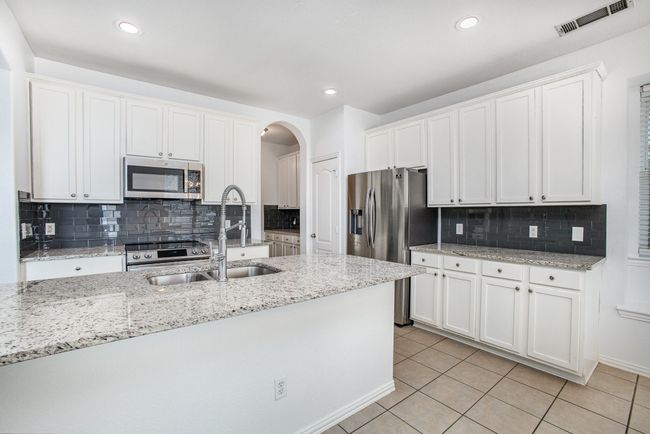 Kitchen with stainless steel appliances, arched walkways, a sink, and light tile patterned floors | Image 11