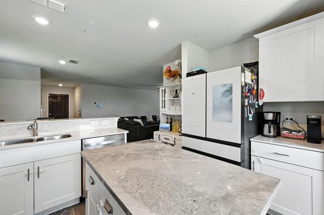 Kitchen featuring freestanding refrigerator, white cabinetry, recessed lighting, a center island, and open floor plan | Image 9