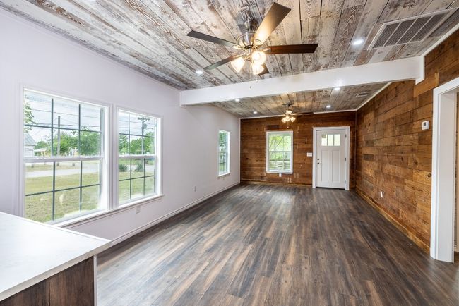 Unfurnished living room featuring wood ceiling and wooden walls | Image 6
