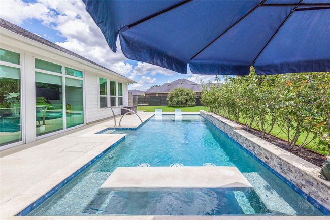 The pool features a built-in table, seamlessly integrated within the water, perfect for entertainment and relaxation. This unique design element invites guests to enjoy poolside conversations and refreshments while staying cool in the refreshing waters. | Image 32