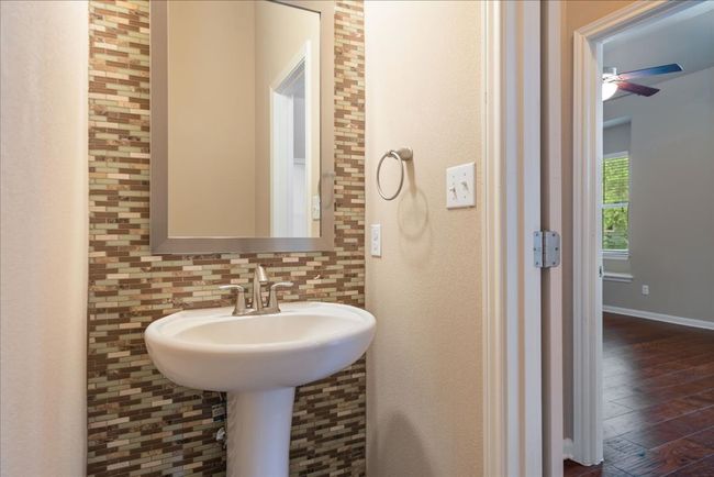 The half bath features a beautiful mosaic wall and pedestal sink. | Image 7