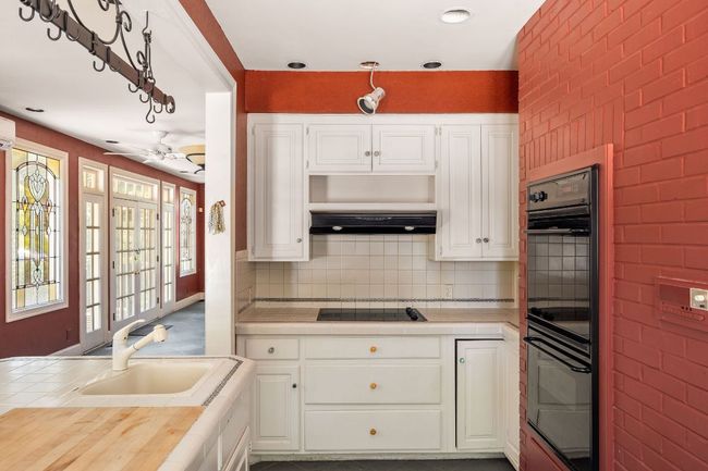 Kitchen featuring black appliances, tile countertops, white cabinets, and ceiling fan | Image 12