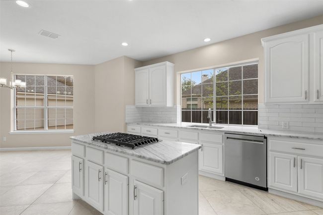 Kitchen featuring a sink, a chandelier, light stone countertops, appliances with stainless steel finishes, and visible vents | Image 10