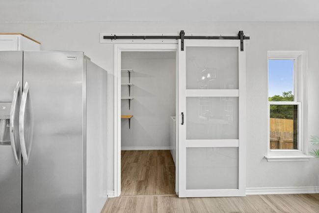 Kitchen with stainless steel refrigerator with ice dispenser, light wood-style flooring, and baseboards | Image 19