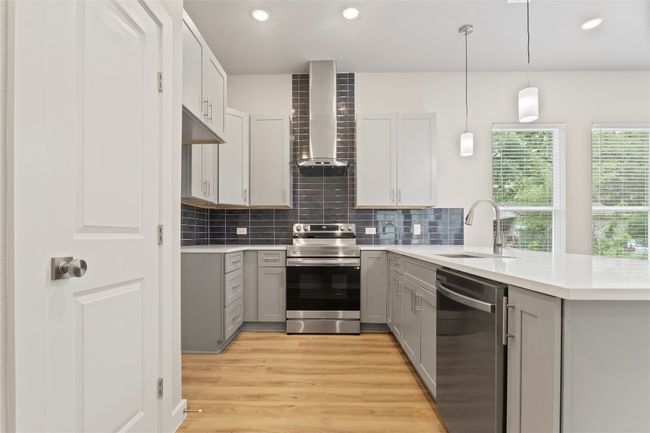 A stunning kitchen with stainless steel appliances, sleek gray cabinetry, and abundant natural light—viewed from a fresh angle. | Image 10