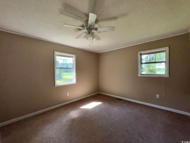 Spare room with healthy amount of natural light, a ceiling fan, carpet, baseboards, and a textured ceiling | Image 14