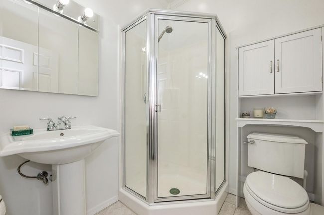 Bathroom with a shower stall, toilet, tile patterned floors, and baseboards | Image 13