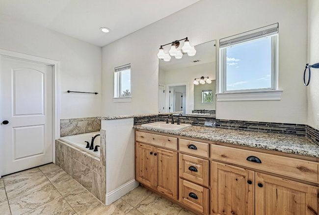 Full bath featuring healthy amount of natural light, marble finish flooring, a garden tub, and vanity | Image 20
