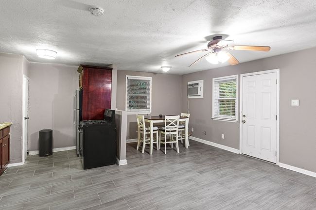 Dining space with a ceiling fan, a textured ceiling, baseboards, a wall mounted AC, and light wood-style flooring | Image 33