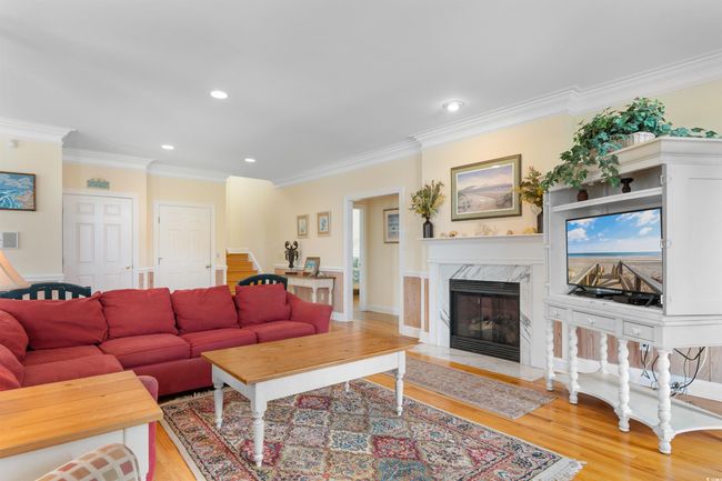 Living room featuring light wood-style floors, ornamental molding, recessed lighting, a high end fireplace, and stairway | Image 13