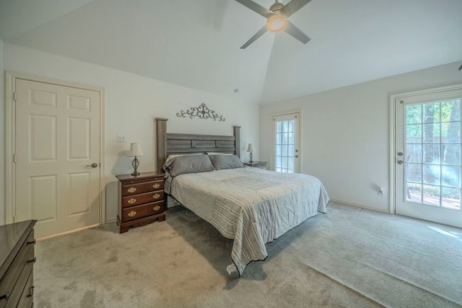 Bedroom with light colored carpet, access to outside sitting area, a ceiling fan, and high vaulted ceiling | Image 17