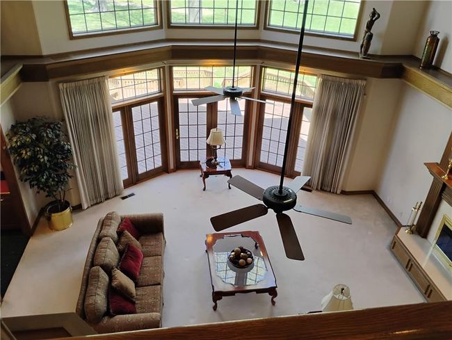 Carpeted living area featuring ceiling fan, a towering ceiling. | Image 61