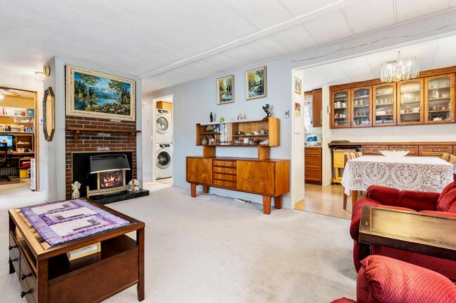 Living room with a chandelier, light carpet, a fireplace, and stacked washer / drying machine | Image 9