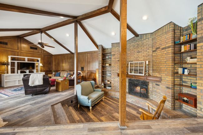 Living Room Boasts Vaulted Ceilings with Wood Beams and Brick Fireplace | Image 7