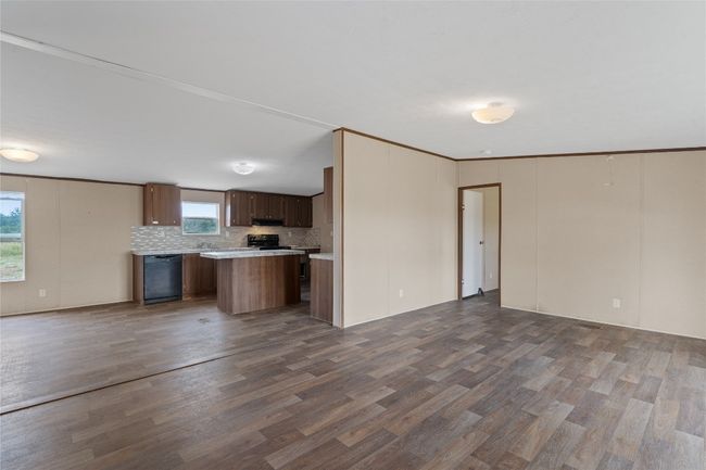 Kitchen featuring black appliances, open floor plan, dark vinyl wood-style flooring, and light countertops | Image 9