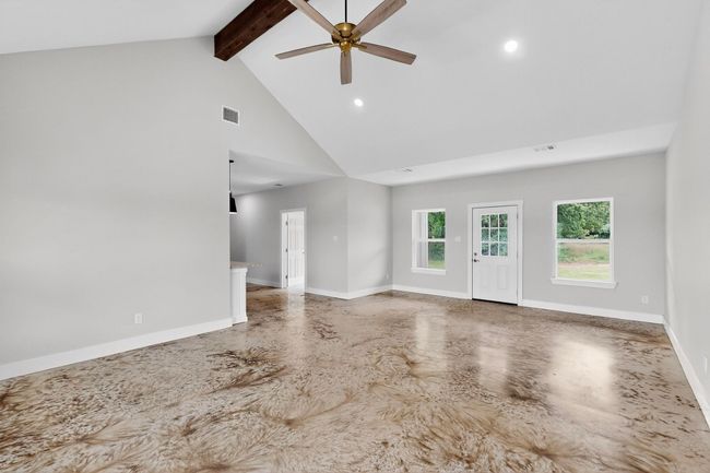 Unfurnished living room featuring high vaulted ceiling, beam ceiling, ceiling fan, recessed lighting, and finished concrete flooring | Image 14