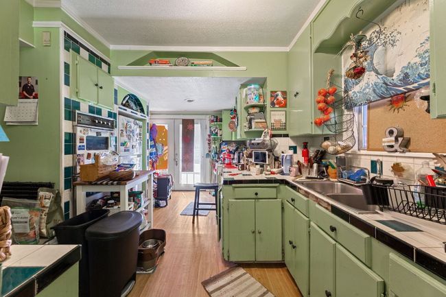 Kitchen with tile countertops, decorative backsplash, light wood-type flooring, and a sink | Image 15