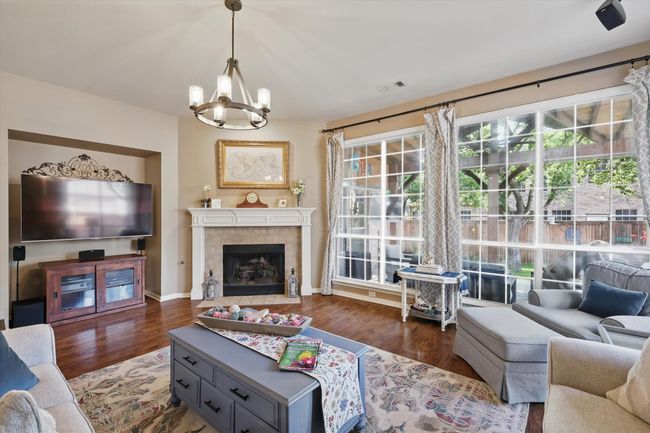 Living area with a chandelier, wood finished floors, baseboards, and a fireplace | Image 5