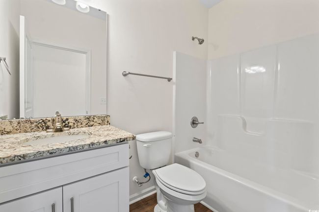 Bathroom featuring vanity, toilet, wood finished floors, bathtub / shower combination, and baseboards | Image 13