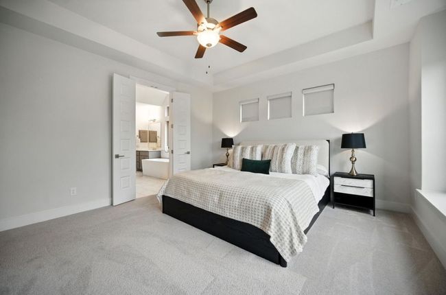 Carpeted bedroom featuring a raised ceiling, a ceiling fan, and ensuite bath | Image 21