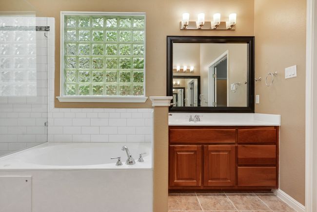The spacious primary suite is a true retreat, complete with a luxurious bath featuring dual vanities, a walk-in shower, a soaking tub, and an oversized walk-in closet. | Image 24